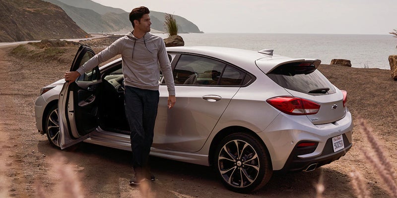 Chevrolet Cruze parked next to an ocean while someone gets out of the vehicle