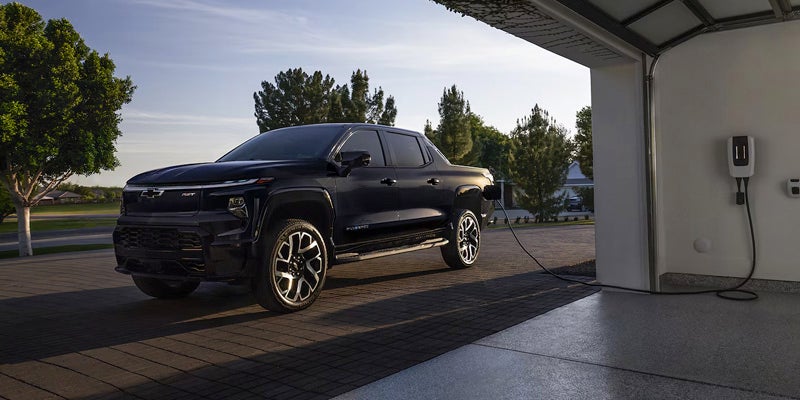 Chevrolet Silverado EV parked on the street as it is being charged in the garage