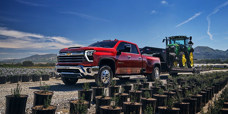 Chevrolet Silverado HD parked next to a big tractor on a farm