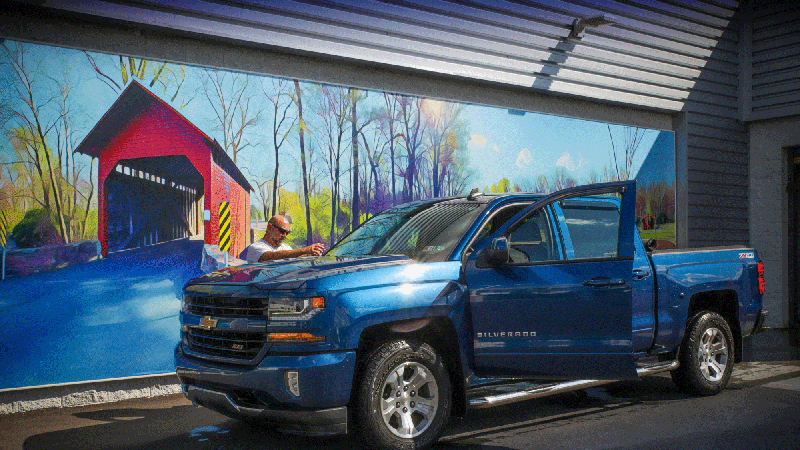 Bald man washing down his brand new blue Silverado at criswell carwash