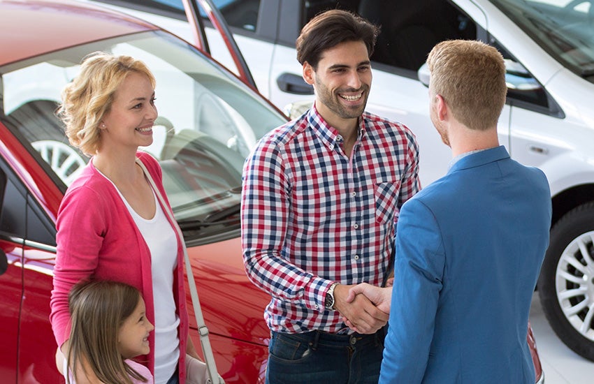 Customers shaking hands with the sales manager after buying a car from Criswell Chevrolet GMC of Gaithersburg